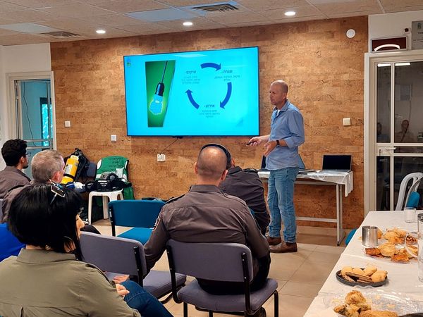 גבר עומד ומציג מצגת ואנשים יושבים ומקשיבים